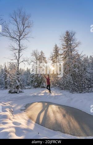 nice woman jumping from Joy in a tranquil winter landscape at sunset with fresh powder snow in the Allgaeu alps, Bavaria, Germany Stock Photo
