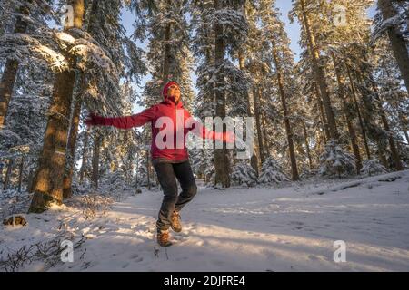 nice woman jumping from Joy in a tranquil winter landscape at sunset with fresh powder snow in the Allgaeu alps, Bavaria, Germany Stock Photo