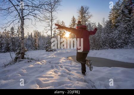 nice woman jumping from Joy in a tranquil winter landscape at sunset with fresh powder snow in the Allgaeu alps, Bavaria, Germany Stock Photo