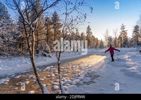 nice woman jumping from Joy in a tranquil winter landscape at sunset with fresh powder snow in the Allgaeu alps, Bavaria, Germany Stock Photo