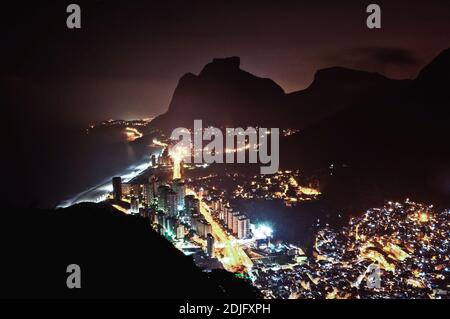 Vista notturna del quartiere di Sao Conrado, un po' di Rocinha Favela e del Monte Pedra da Gavea a Rio de Janeiro, Brasile Foto Stock