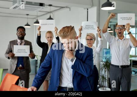 gruppo di lavoratori scovare direttore per cattiva direzione, hanno bisogno di altri boss. dipendenti stare con carta con le descrizioni in background, nessuna violenza a wor Foto Stock