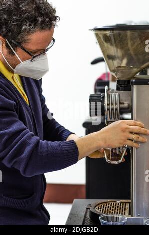 Un barista macina alcuni chicchi di caffè per preparare l'espresso Foto Stock