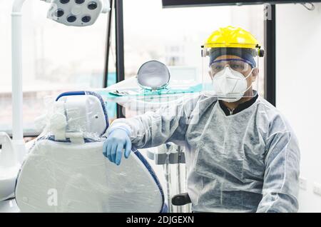 Ritratto di un giovane dentista peruviano con maschera e visiera in un ufficio odontoiatrico. COVID - 19 protezione antivirus Foto Stock