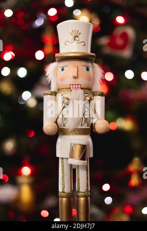 Statuetta frontale classico soldato batterista nutcracker con bianco e oro Uniforme e tamburo davanti all'albero di Natale sfocato Foto Stock