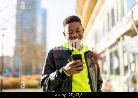 Giovane uomo che usa lo smartphone all'aperto in ambiente urbano Foto Stock