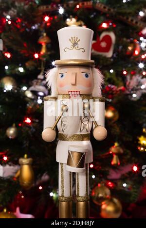 Statuetta frontale classico soldato batterista nutcracker con bianco e oro Uniforme e tamburo di fronte all'albero di Natale Foto Stock