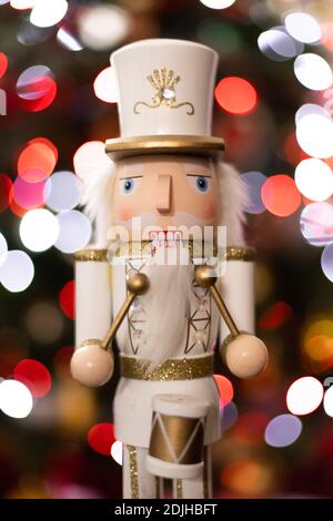 Statuetta frontale classico soldato batterista nutcracker con bianco e oro Uniforme e tamburo davanti all'albero di Natale sfocato Foto Stock