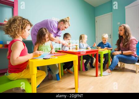 Gli studenti prescolare con un tutor di attività in classe d'arte Foto Stock