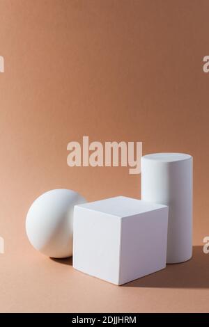 Forme geometriche tridimensionali bianche su sfondo marrone chiaro Foto Stock