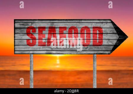 Cartello di legno di Red Seafood con una spiaggia sullo sfondo Foto Stock