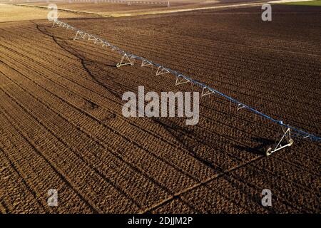 Veduta aerea del sistema di irrigazione a perno centrale sul campo arato da drone pov, agricoltura e attrezzature agricole Foto Stock