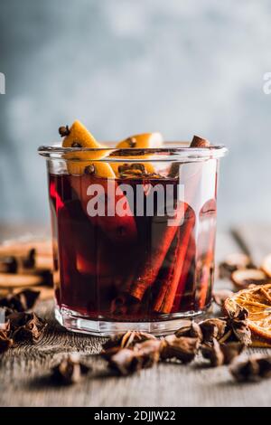 VIN brulé rosso con arance e spezie diverse in vetro su sfondo rustico. Cibo di Natale. Decorazioni invernali. Messa a fuoco selettiva. Dept. Bassa Foto Stock