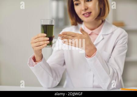 Dietista professionista che tiene la bevanda detox e che dice circa la relativa salute vantaggi Foto Stock