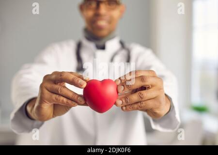 Medico che tiene il cuore rosso e promuove uno stile di vita sano e la prevenzione di malattie cardiache Foto Stock