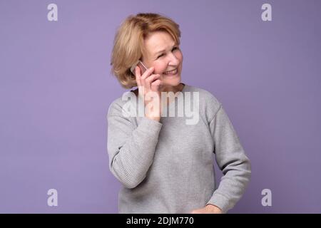 Donna caucasica matura che ride mentre parla sul cellulare. Scatto in studio Foto Stock