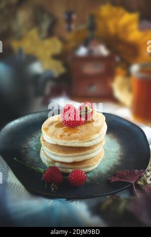 impila di deliziosi pancake su un piatto con lamponi e sciroppo. Foto Stock