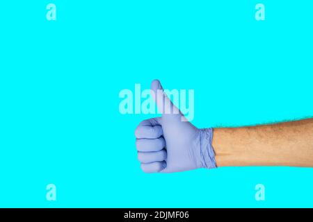 Gesti delle mani. Mano umana in guanto di lattice con il simbolo di ok isolato su sfondo blu al neon con spazio per la copia. Foto Stock