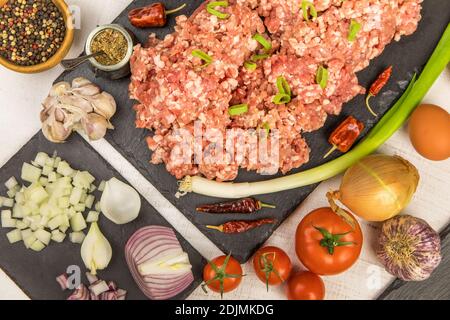 Meatloaf appena preparato pronto per il forno con ingredienti. Carne tritata con spezie al peperoncino e salsiccia. Preparazione di un classico polpettone con manzo macinato. Foto Stock