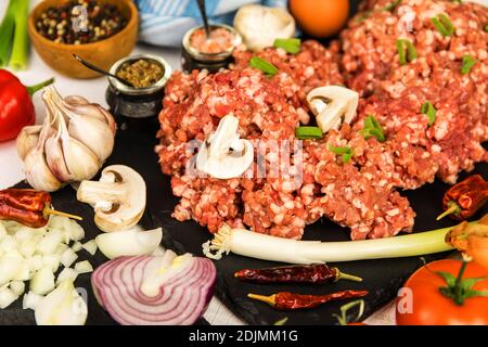 Meatloaf appena preparato pronto per il forno con ingredienti. Carne tritata con spezie al peperoncino e salsiccia. Preparazione di un classico polpettone con manzo macinato. Foto Stock