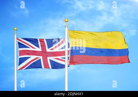 Regno Unito e Colombia due bandiere su flagpoli e blu cielo nuvoloso Foto Stock