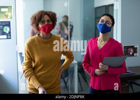 Ritratto di due colleghi di razza mista che indossano maschere ufficio Foto Stock