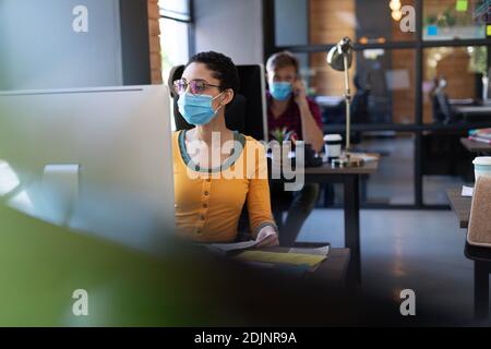 Diversi colleghi indossano maschere che lavorano con i computer in ufficio scrivanie Foto Stock