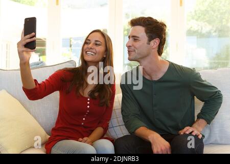 Coppia caucasica che prende selfie con smartphone seduto sul divano sorridente Foto Stock