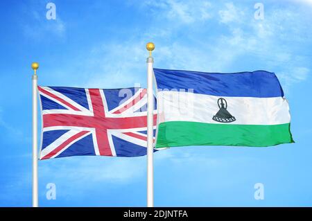 Regno Unito e Lesotho due bandiere su flagpoli e blu cielo nuvoloso Foto Stock