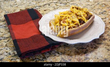 Chili cane fatto in casa con formaggio cheddar su un piatto bianco. Foto Stock