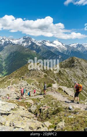 Sabbia a Taufers, Provincia di Bolzano, Alto Adige, Italia. Escursionisti sul sentiero panoramico nella zona escursionistica di Speikboden. Sullo sfondo le Alpi Zillertal con le cime Schwarzenstein e Grosser Löffler Foto Stock