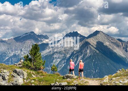 Sabbia a Taufers, Provincia di Bolzano, Alto Adige, Italia. Escursionisti sul sentiero panoramico nella zona escursionistica di Speikboden con vista sul Gruppo Rieserferner con le cime di Schneebiger Nock, Fensterleekofel e Windschar. Foto Stock