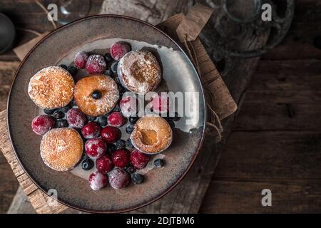 Piatto con frutti di bosco surgelati e panna su fondo di legno. Foto Stock