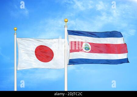 Giappone e Costa Rica due bandiere su flagpoli e blu cielo nuvoloso Foto Stock