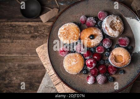 Bacche e prugne surgelate su un piatto marrone. Foto Stock