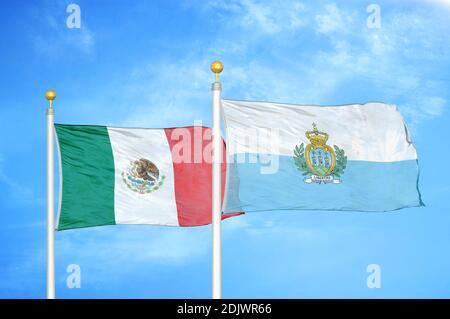 Messico e San Marino due bandiere su flagpoli e blu cielo nuvoloso Foto Stock