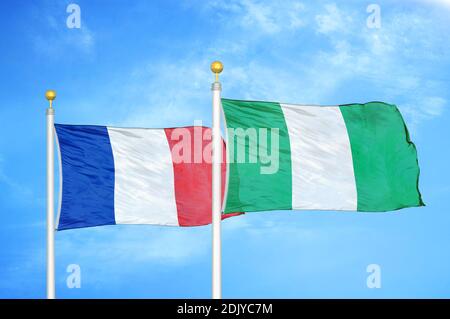 Francia e Nigeria due bandiere su paletti e blu nuvoloso cielo Foto Stock