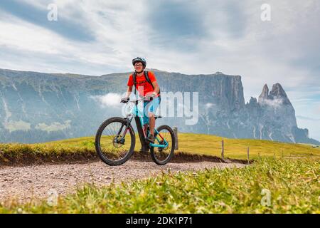 Giovane (22 anni) in bicicletta elettrica lungo un sentiero alpino in Alpe di Susi, Dolomiti, Alto Adige/Südtirol, Italia, Europa Foto Stock