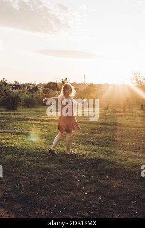 Giovane bionda con la zest per la vita, danzando tra gli ulivi al tramonto in Sardegna Foto Stock