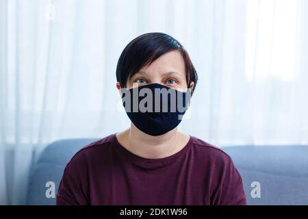 Primo piano ritratto donna, giovane donna che indossa a casa maschera igienica viso per prevenire infezioni, malattie o influenza e 2019-nCoV. Sfondo nero Foto Stock