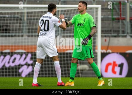 Augusta, Germania. 13 Dicembre 2020. Calcio: Bundesliga, FC Augusta - FC Schalke 04, 11° incontro nella WWK-Arena. Daniel Caligiuri (l) di Augusta e il portiere Rafal Gikiewicz stanno aggrappando le mani. Credito: Stefan Puchner/dpa - NOTA IMPORTANTE: In conformità con le norme del DFL Deutsche Fußball Liga e del DFB Deutscher Fußball-Bund, è vietato sfruttare o sfruttare nello stadio e/o nel gioco le fotografie scattate sotto forma di sequenze di immagini e/o serie di foto di tipo video./dpa/Alamy Live News Foto Stock