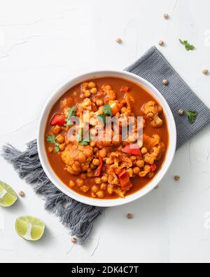 Un colpo verticale di chickpea curry chana masala con lime in una ciotola su un surf bianco Foto Stock