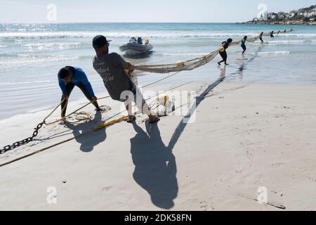 Un equipaggio di avvistatori di squalo dispiega una barriera netta di esclusione dello squalo a Fish Hoek Beach, False Bay, Città del Capo, Sud Africa. Protezione da bacon. Turismo. Foto Stock