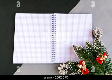 Apri il quaderno mockup e i rami dell'albero di Natale su sfondo a colori. Modello per il biglietto di auguri per il nuovo anno. Buon Natale e felice anno nuovo Foto Stock
