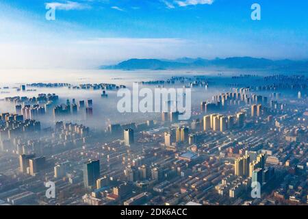 Le nuvole dell'avvento scorrono lentamente tra gli edifici urbani, che si profilano come una zona fieristica nella città di Shijiazhuang, provincia di Hebei, nella Cina settentrionale, il 12 dicembre Foto Stock