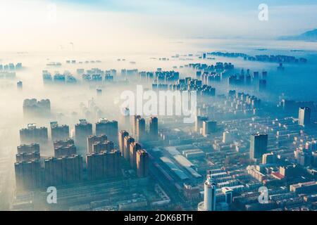 Le nuvole dell'avvento scorrono lentamente tra gli edifici urbani, che si profilano come una zona fieristica nella città di Shijiazhuang, provincia di Hebei, nella Cina settentrionale, il 12 dicembre Foto Stock