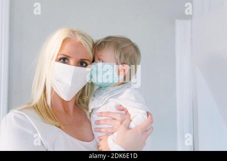 La madre e il figlio abbracciano le maschere per il viso Foto Stock