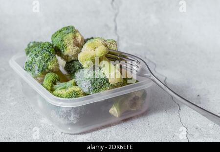 fuoco selettivo. broccoli surgelati in un contenitore trasparente. copyspace. sfondo chiaro Foto Stock