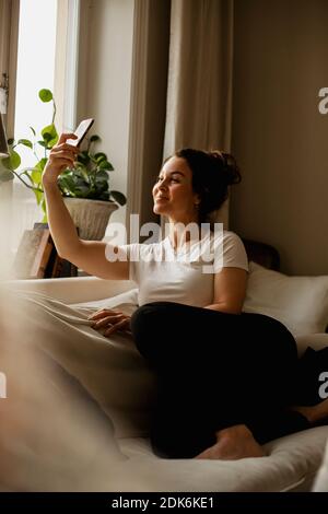 Donna sul divano tenendo selfie Foto Stock