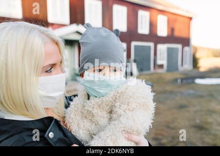Madre e bambino che indossano maschere per il viso Foto Stock